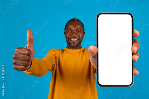 Cheerful african american man showing cell phone and thumb up