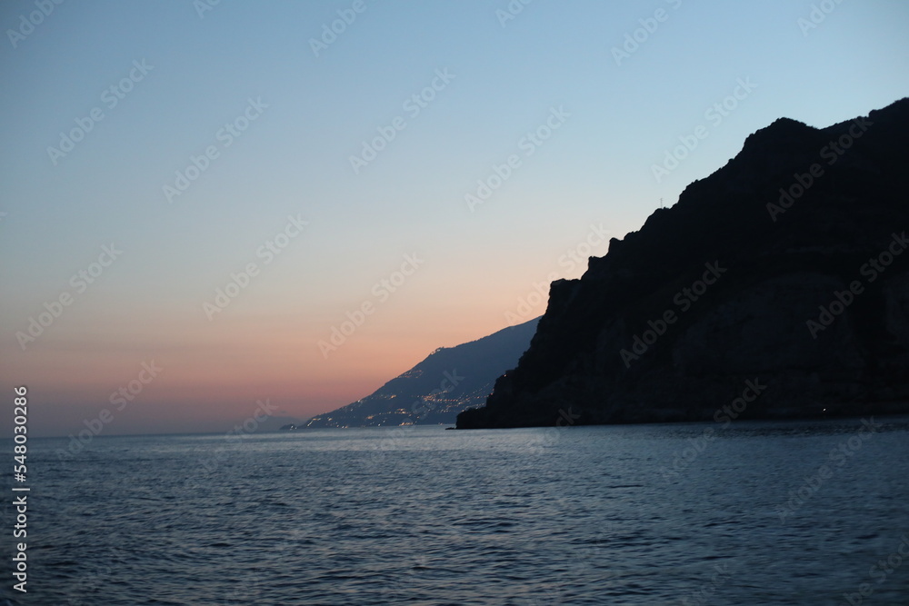 Sunset view of the sea and mountain. Scenic view of the coast of island of the region. Evening landscape with mountains and sea. Dusk time lapse. Seascape with blue sky and clouds. Sea and rocks
