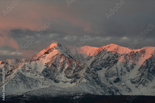 Russia. The South of Western Siberia, the Altai Mountains. Illuminated by the crimson morning light, the peaks of the North Chui Mountain Range along the Chui tract.
