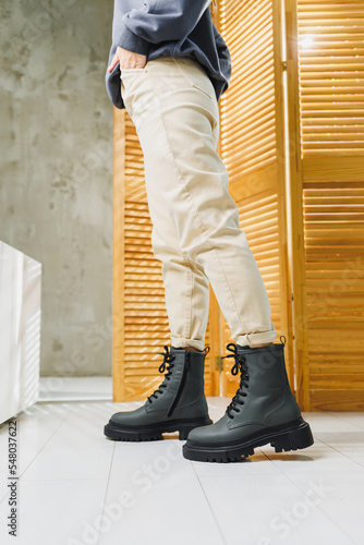 Fashionable women's stylish leather boots. Green women's genuine leather boots on feet close-up. New collection of winter shoes for stylish girls.