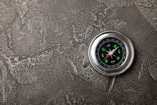 Classic round compass on a black textured background. Symbol of tourism with a compass, travel with a compass and outdoor activities. Close-up. Place for text. copy space