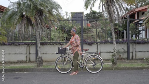 Mujer afro caribeña en bicicleta se detiene para ofrecer a clientes en la calle los productos que vende   photo