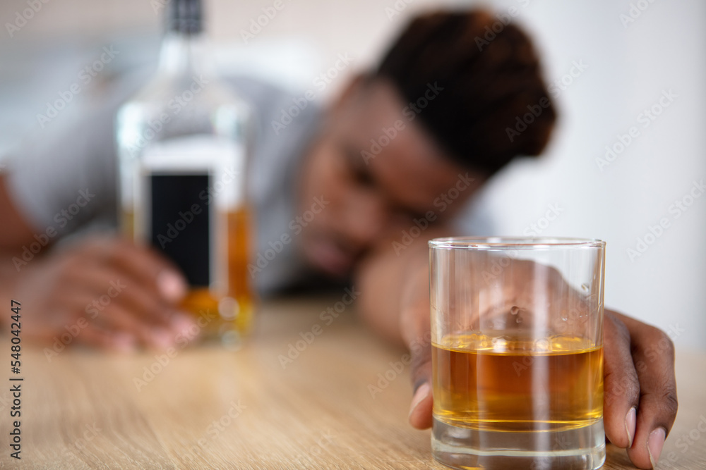 intoxicated man slumped on table holding glass intoxicated man slumped on table holding glass