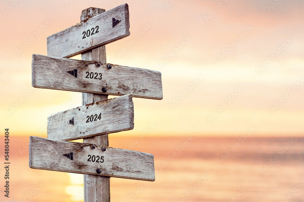 2022 2023 2024 2025 text written on wooden signpost outdoors at the beach during sunset - obrazy, fototapety, plakaty 