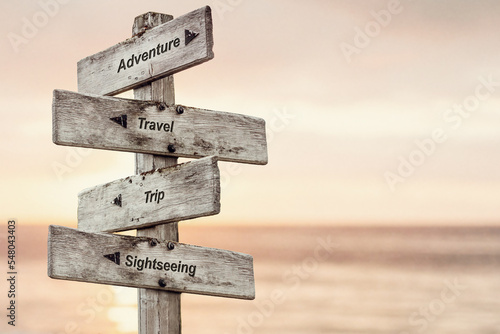 adventure travel trip sightseeing text written on wooden signpost outdoors at the beach during sunset