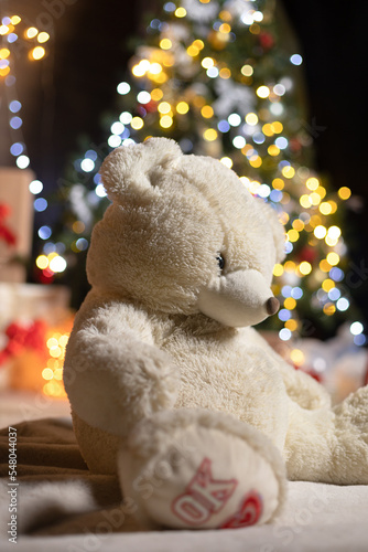 A sad teddy bear in front of the Christmas tree with his head down and says ok, ok I feel