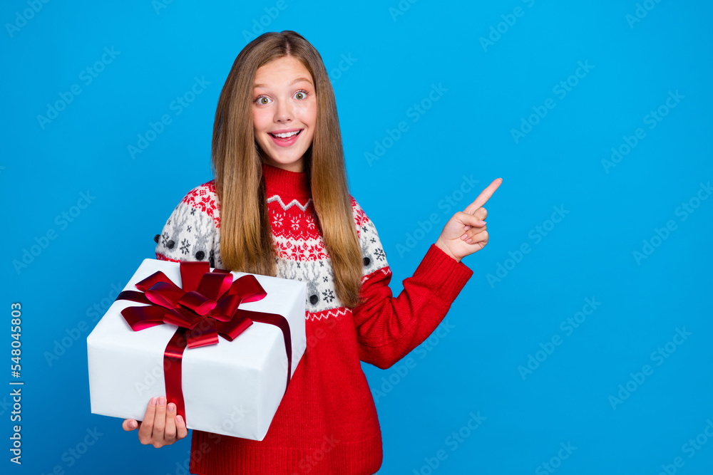 Photo of impressed girl with straight hairstyle dressed red pullover hold present directing empty space isolated on blue color background Photo of impressed girl with straight hairstyle dressed red pullover hold present directing empty space isolated on blue color background