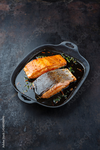 Traditional Japanese salmon fish teriyaki filet with soy souce and spinach as top view in a Nordic design pan with copy space