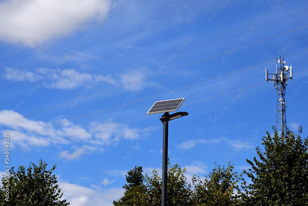 landscape lanterns with solar panels, cell tower against the background of trees and blue sky landscape lanterns with solar panels, cell tower against the background of trees and blue sky
