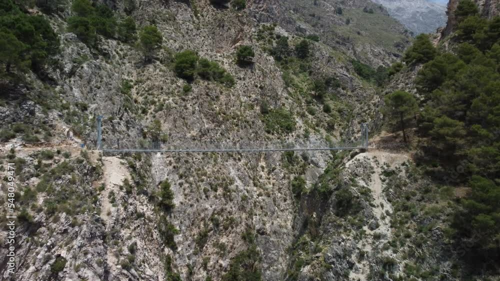 Aerial view of suspension bridge of 'El Saltillo Canillas de Aceituno' in the beautiful mountain landscape of Canillas de Aceituno on a sunny day, Malaga, Spain Aerial view of suspension bridge of 'El Saltillo Canillas de Aceituno' in the beautiful mountain landscape of Canillas de Aceituno on a sunny day, Malaga, Spain