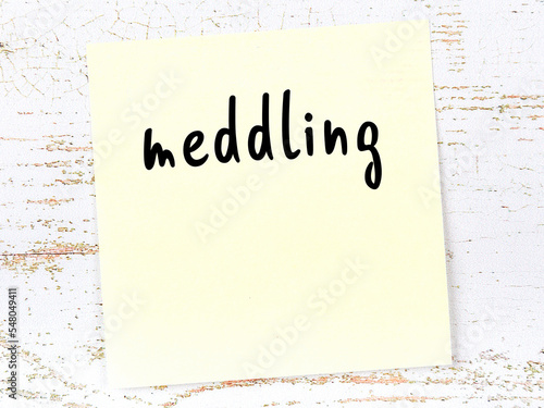 Slika na platnu Yellow sticky note on wooden wall with handwritten word meddling