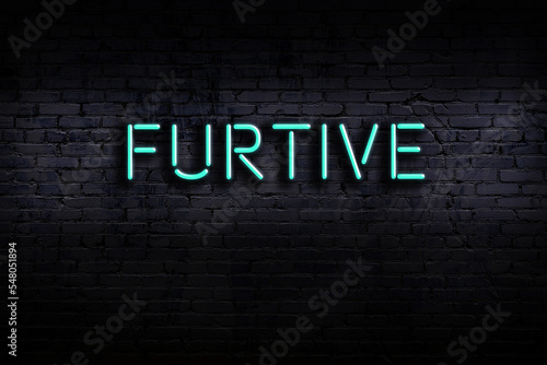 Neon sign. Word furtive against brick wall. Night view photo