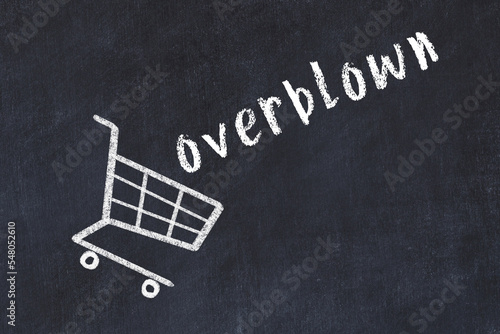 Chalk drawing of shopping cart and word overblown on black chalboard. Concept of globalization and mass consuming photo