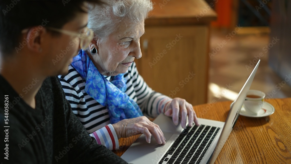 Closeup of elderly senior woman learning to use a laptop computer from teen male grandson with tea. Closeup of elderly senior woman learning to use a laptop computer from teen male grandson with tea.