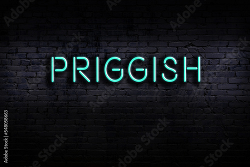 Tableau sur toile Neon sign. Word priggish against brick wall. Night view