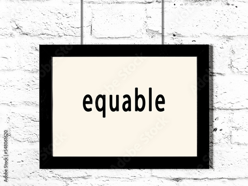 Black frame hanging on white brick wall with inscription equable