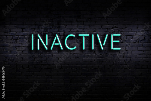 Neon sign. Word inactive against brick wall. Night view photo