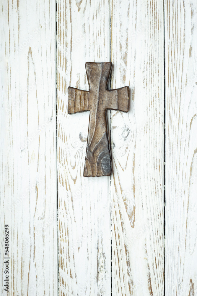 dark wooden cross on white wooden board in vertical position. copy of space. space for text. background for religious event design.