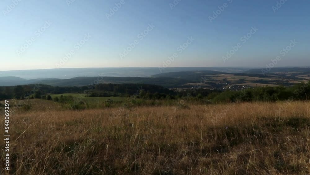 Rural landscape from a mountain with villages, meadows, fields, forests, trees on the horizon and yellow waving grass in the foreground Rural landscape from a mountain with villages, meadows, fields, forests, trees on the horizon and yellow waving grass in the foreground