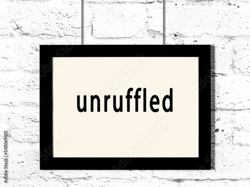 Black frame hanging on white brick wall with inscription unruffled