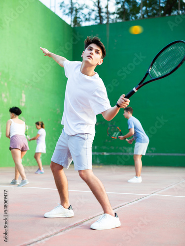 Sports active young man during friendly doubles couple match. Two men playing frontenis together outdoor