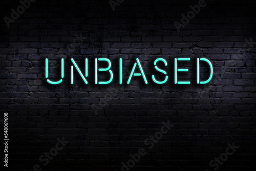 Neon sign. Word unbiased against brick wall. Night view photo