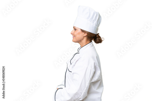 Middle-aged chef woman over isolated background in lateral position photo