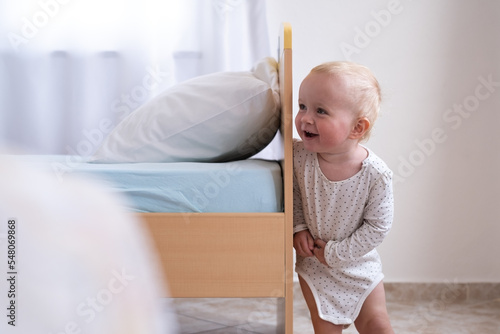 Caucasian baby girl playing hide and seek with her parents. photo