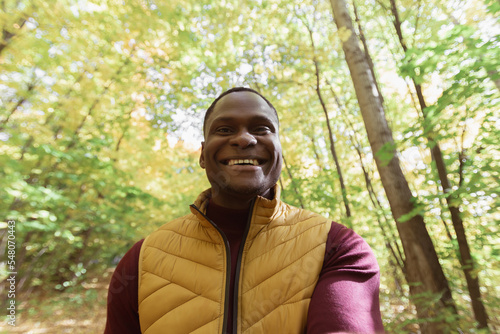 African American man taking a self portrait with a smartphone in autumn fall park copy space. Happy people, season and new normality concept photo