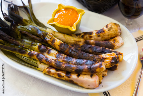 Grilled calcots with romesco sauce. National Catalan winter dish served in restaurant photo