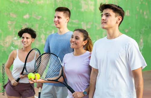 Group photo of positive women and young men frontenis players standing on outdoor fronton.