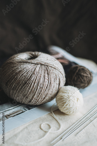 Skein and balls of woolen yarn and knitting needles for hand knitting.