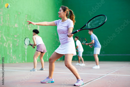 Sportive woman in shorts and t-shirt playing frontenis on outdoors court