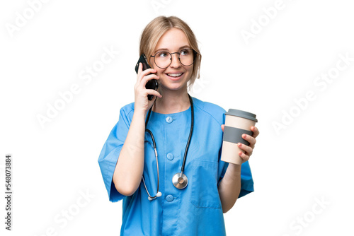 Young nurse English woman over isolated background holding coffee to take away and a mobile