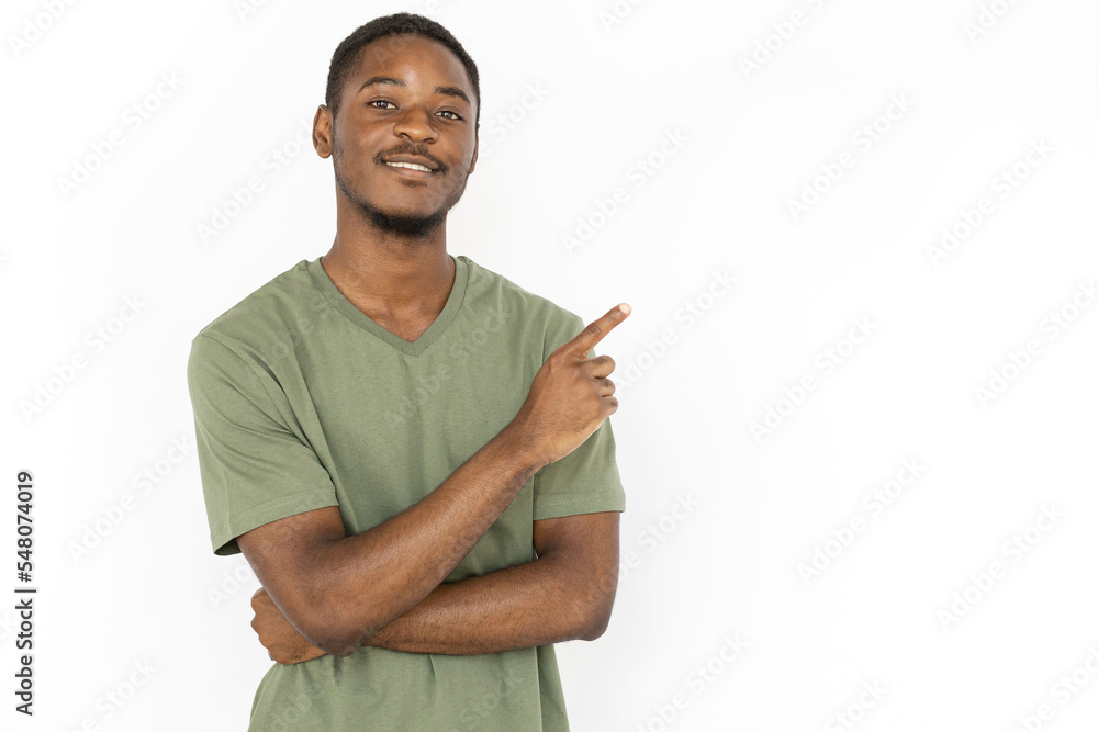 Cheerful young man pointing with finger at copyspace advertising something. Male African American model in green T-shirt smiling and presenting advertisement. Advertising, social media concept Cheerful young man pointing with finger at copyspace advertising something. Male African American model in green T-shirt smiling and presenting advertisement. Advertising, social media concept