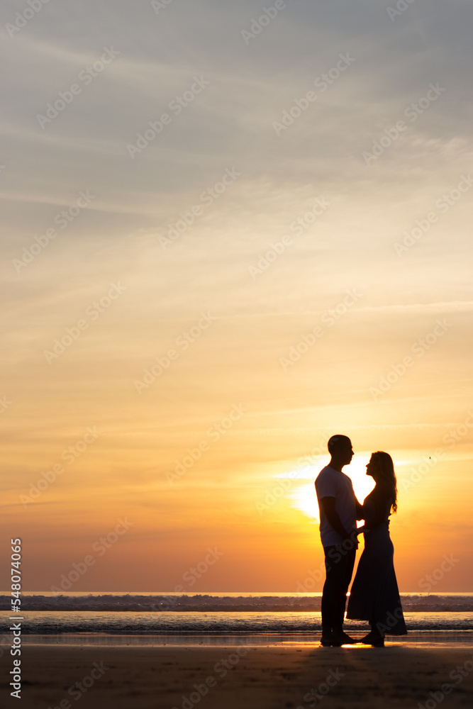 Gentle family walking on beach at sunset. Man and woman in casual clothes strolling near water at dusk. Love, family, nature concept Gentle family walking on beach at sunset. Man and woman in casual clothes strolling near water at dusk. Love, family, nature concept