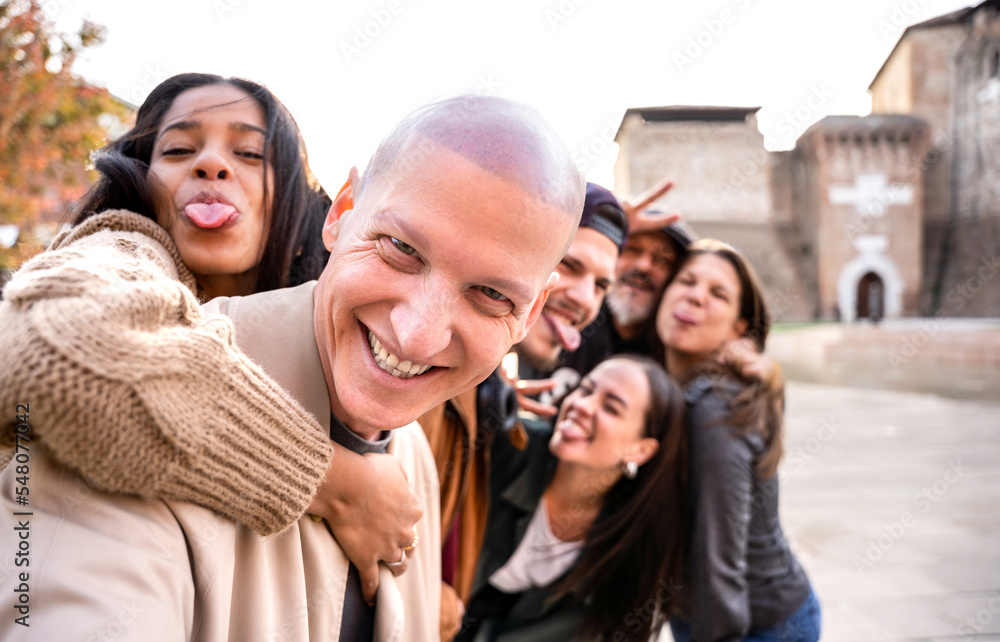 Happy men and women having fun together hanging out -Multicultural friends group taking selfie picture outdoors - Making strange face with tongue out - Focus on first guy Happy men and women having fun together hanging out -Multicultural friends group taking selfie picture outdoors - Making strange face with tongue out - Focus on first guy