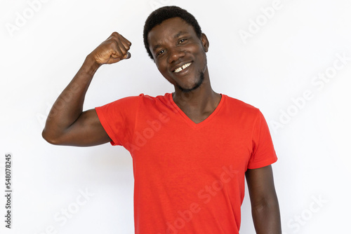 Proud man tensing bicep. Young African American male model showing muscles and smiling. Portrait, studio shot, strength concept