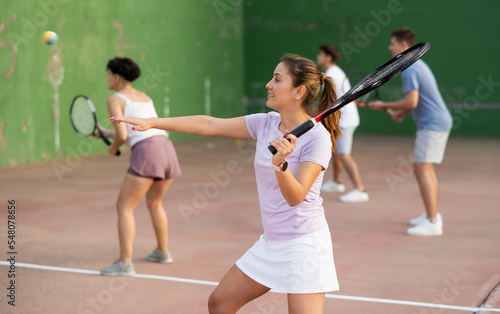 Focused woman playing frontenis with partners at sunny day, healthy lifestyle concept © JackF