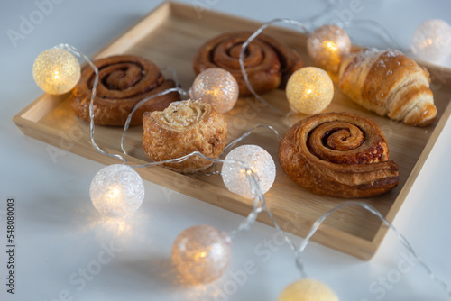 Homemade cinnamon buns with spices and caramel on tray with garland