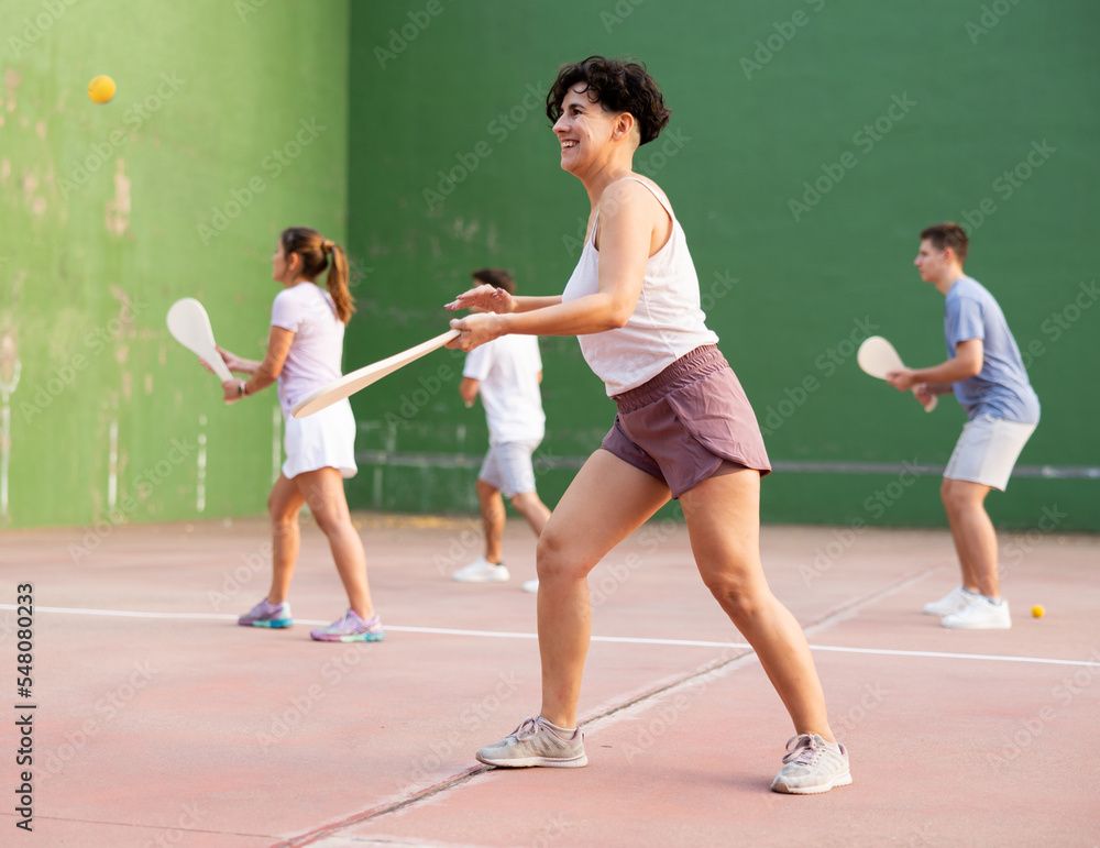 Young sporty woman performing basic strokes during paleta fronton group training