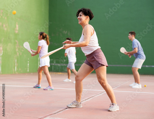 Young sporty woman performing basic strokes during paleta fronton group training © JackF