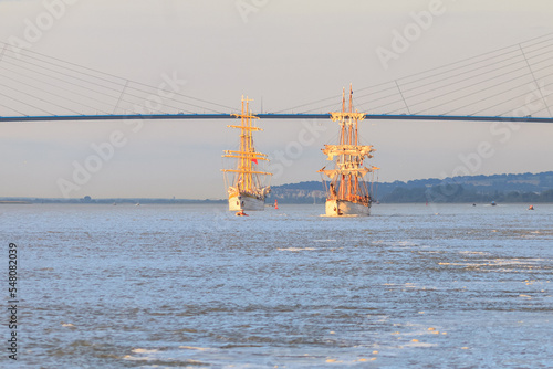 HONFLEUR, NORMANDY, FRANCE: Armada 2019 Grande Parade, tall ships Mircea and Le Français sailing in the Seine Estuary, in front of Normandy Bridge, with warm evening light photo