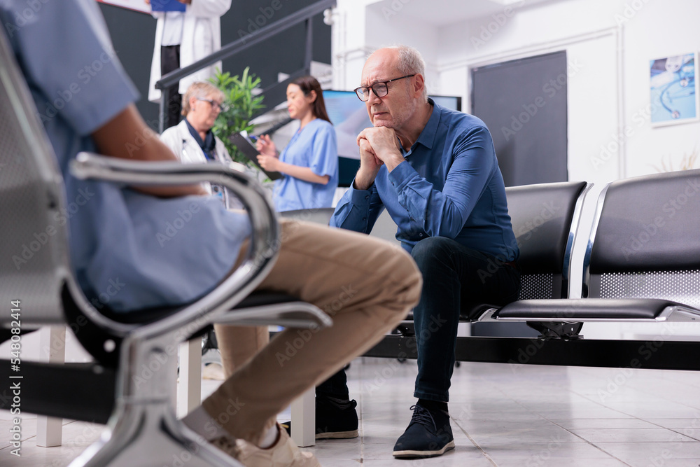 Stressed exhausted senior man patient sitting on chair in hospital reception waiting for physician medic to discuss disease diagnosis during checkup visit consultation. Health care service and concept Stressed exhausted senior man patient sitting on chair in hospital reception waiting for physician medic to discuss disease diagnosis during checkup visit consultation. Health care service and concept