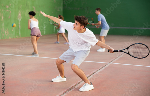 Young male sportsman preparing to hit ball with racket. Frontenis game on outdoor court © JackF