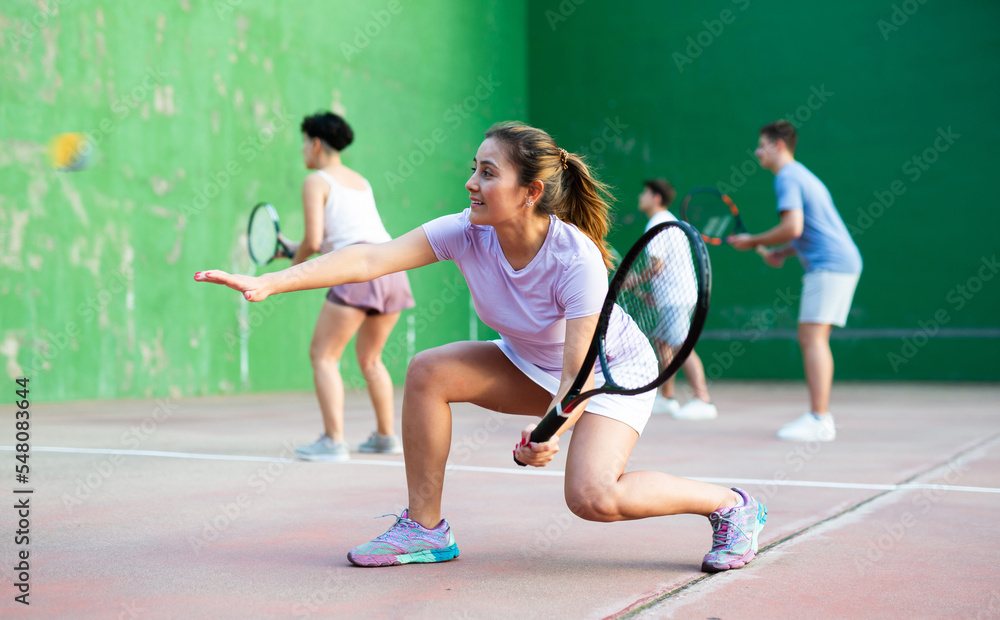 Focused woman playing frontenis with partners at sunny day, healthy lifestyle concept