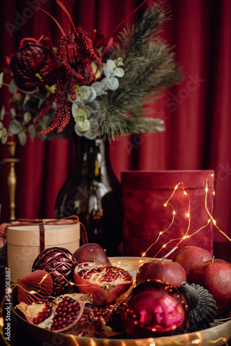 
Red velvet still life. A beautiful arrangement of items with fir branches in a bouquet, a gift box with a crane on a tray and a garland. Beautiful red screensaver for your phone