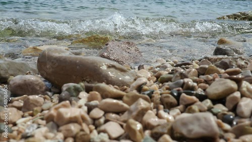 Adriatic Sea, Montenegro Mediterranean. Calm waves of salt water splash against the rocky shore of the plage. Clear water and multi-colored rounded pebbles. Travel business. Sunny beach vacation. photo