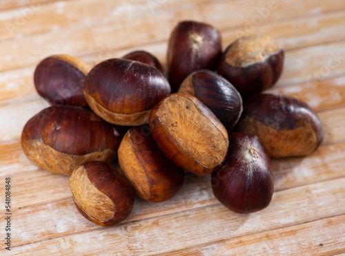 Pile of unpeeled sweet chestnuts on wooden table