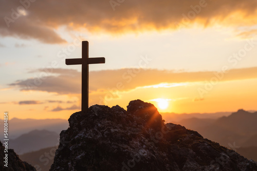 Foto Silhouettes of crucifix symbol on top mountain with bright sunbeam on the colorf